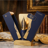 Une présentation de produits haut de gamme montrant le flacon Risala Autograph 100ml niché dans son coffret cadeau bleu et or inspiré d'un stylo-plume, sur une surface en marbre.